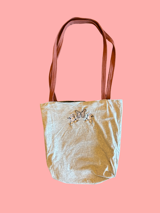 Gold glittery bag with butterfly embellishments on a pink background